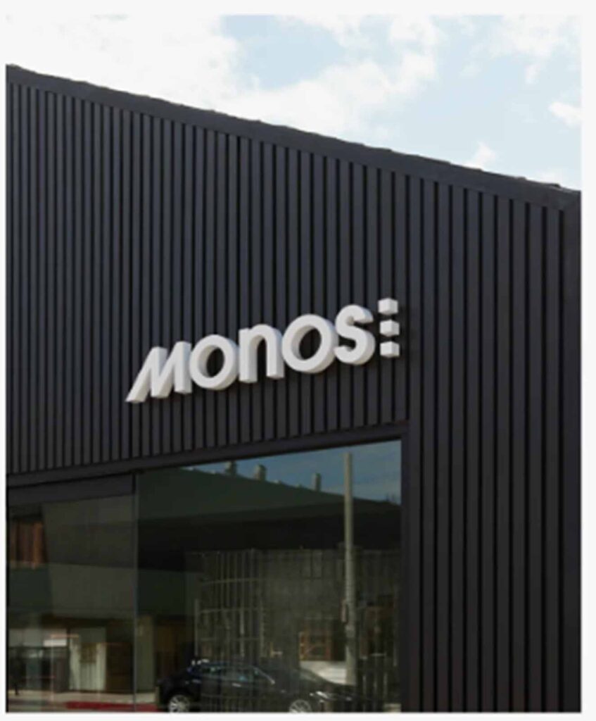 he dark wood vertical facade of the Monos storefront on Abbot Kinney with an illuminated white brand logo.