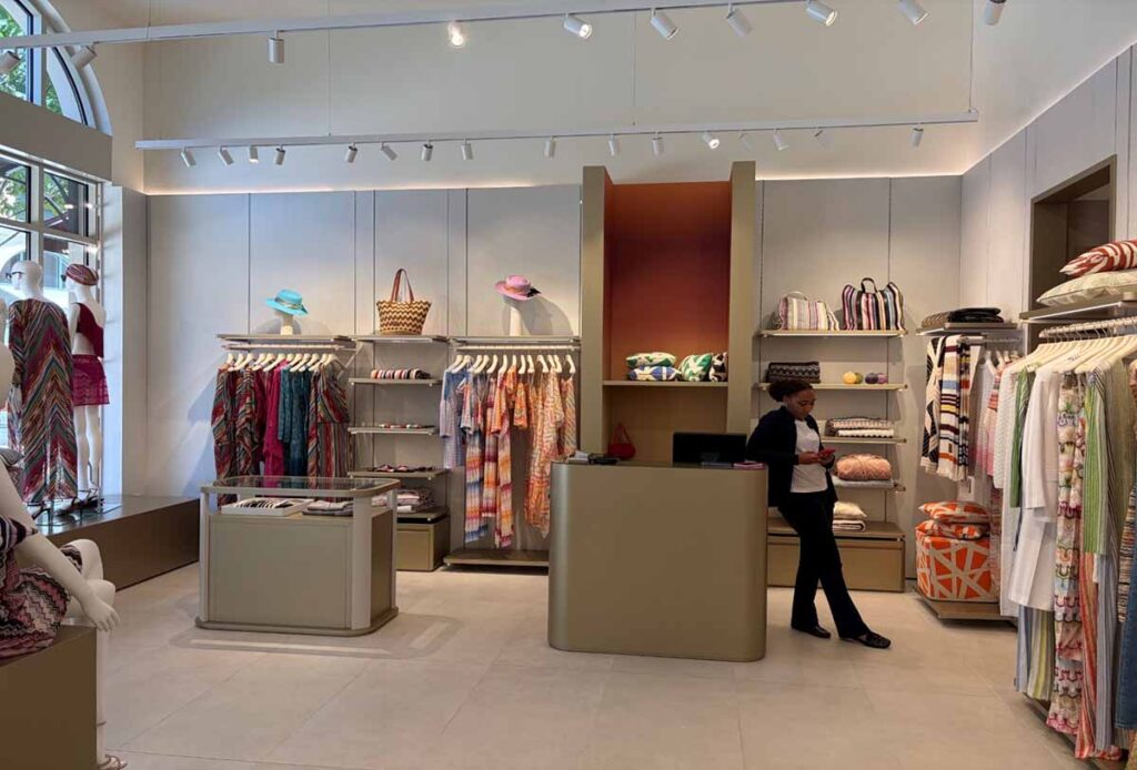 A luxury contemporary retail showroom interior completed by MOMA Construction Group for a boutique at Belmont Park, customized minimalist shelving, clothing racks, and modern track lighting illuminating the space.
