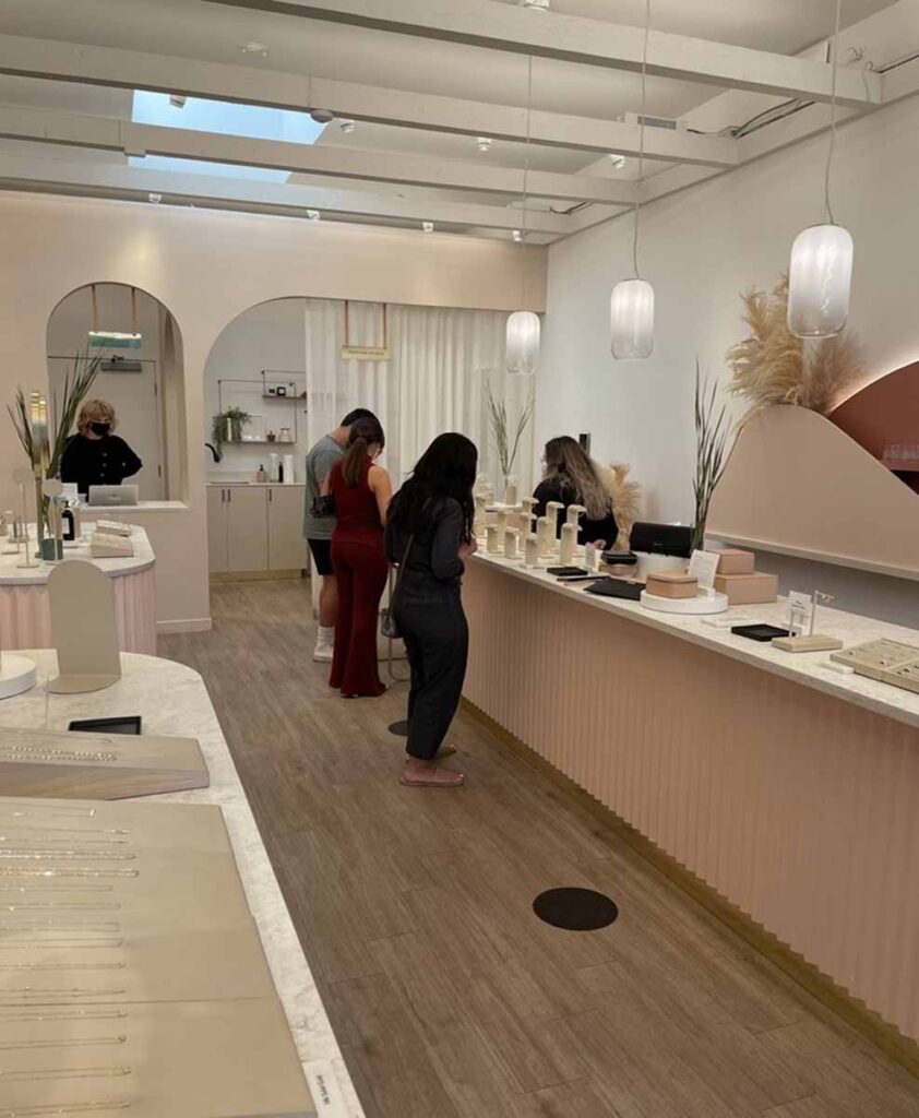 Modern jewelry showroom with a custom curved pink terrazzo-topped cash wrap counter and modern frosted glass pendant lighting.