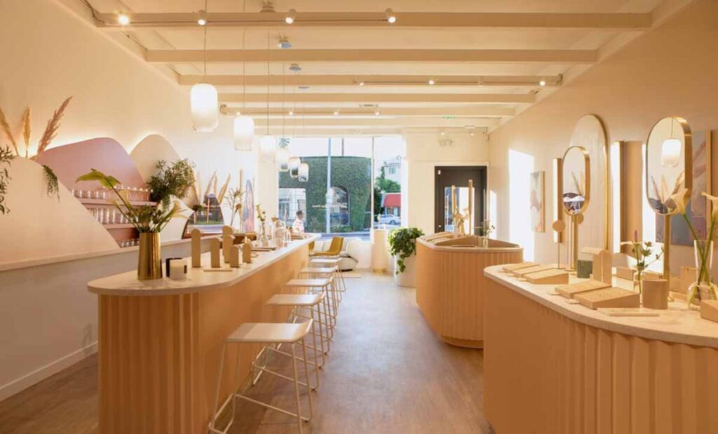 MOMA Construction Group features a wide-angle view of a luxury jewelry showroom with fluted pink service counters, polished wood flooring, and hanging frosted glass pendant lights.