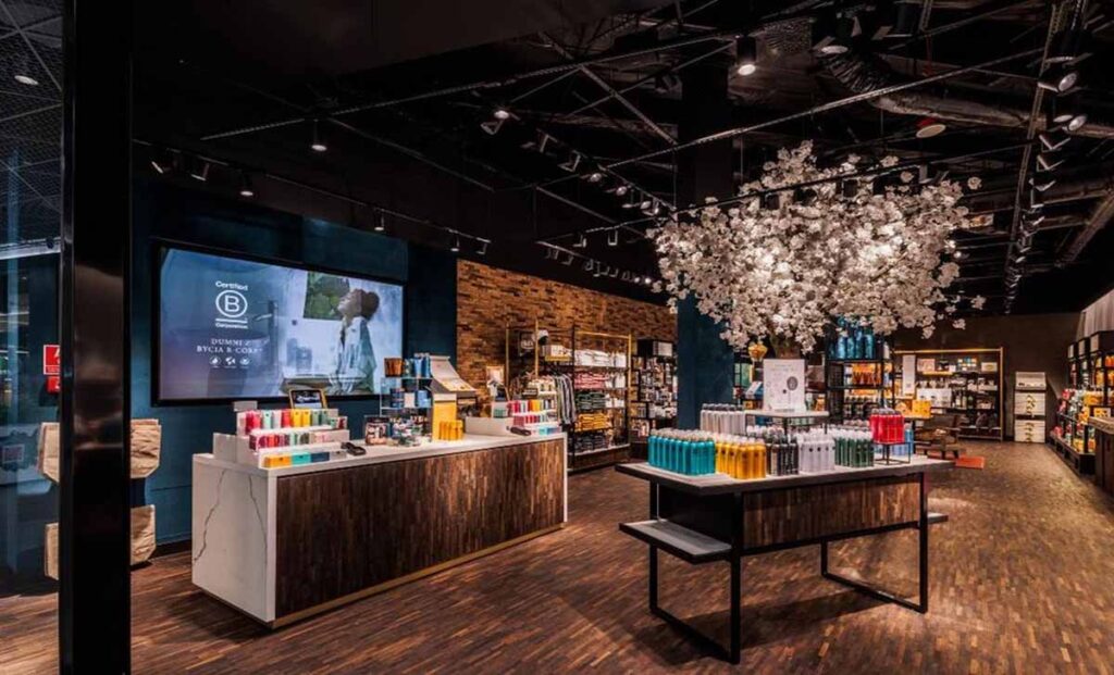 commercial retail sowroom fit-out by MOMA Construction Group featuring a custom premium marble-edged cash wrap island counter, a large overhead floral branch light fixture, and built-in wood display shelving inside a cosmetics boutique.