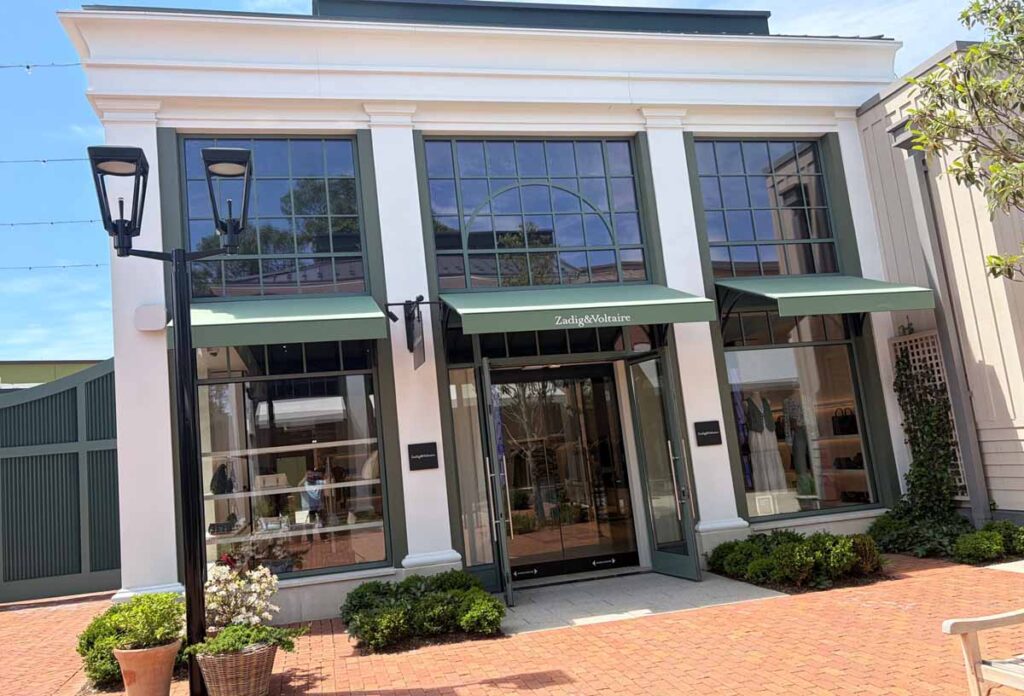 Premium fashion showroom exterior featuring grid windows and street lamps with beautiful flowers.