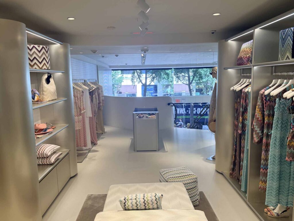 Modern retail storefront interior on Madison Avenue showcasing premium apparel displays, contemporary rack layouts and custom accent seating.