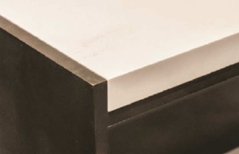 A close-up view of a custom retail display counter built by MOMA Construction Group for the Vince showroom, featuring a minimalist dark wooden frame supporting a thick, smooth light stone surface.